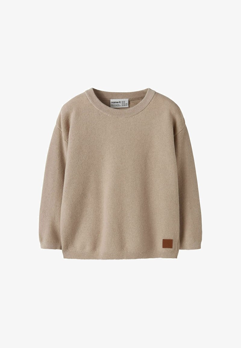 Pull en maille beige à manches longues avec col rond et petite pièce rectangulaire marron près de l'ourlet, conçu pour les enfants.