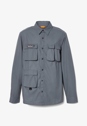 Long-sleeve, gray shirt made of a lightweight fabric. Features four front pockets, snap buttons, and a collar with an orange interior accent.
