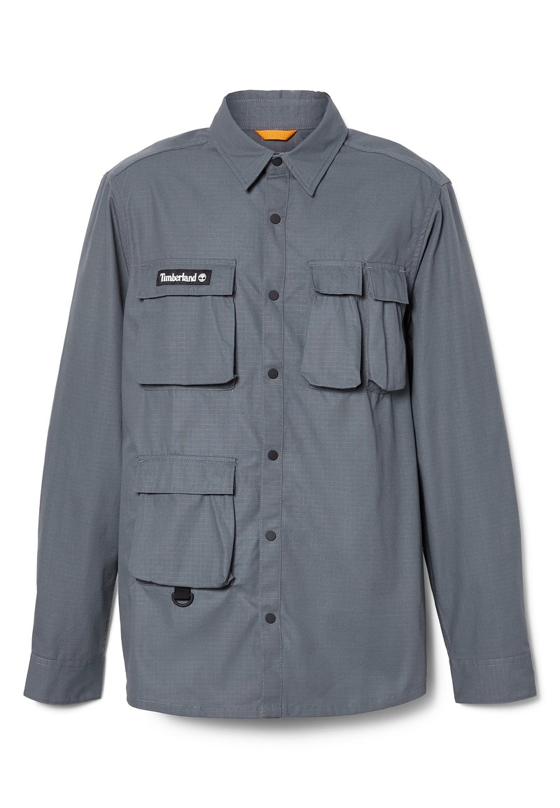 Szara koszula z długim rękawem wykonana z lekkiego materiału. Posiada cztery przednie kieszenie, zatrzaski oraz kołnierz z pomarańczowym akcentem wewnątrz.