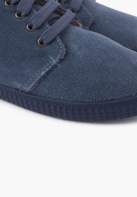 Sneakers in suede blu navy con suola in gomma testurizzata, punta rotonda e lacci piatti. Presentano dettagli cuciti e occhielli metallici per i lacci.