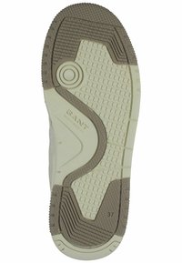 Gummisulor i ljuskräm med texturerad yta, med ett mörkbrunt accentmönster och präglad varumärkeslogotyp. Storlek 37 angiven.