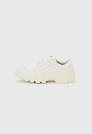 Witte chunky sneaker met dikke zool en veters aan de voorkant, met de tekst "ROMBAUT CORE" aan de zijkant, getoond op een eenvoudige lichte achtergrond.