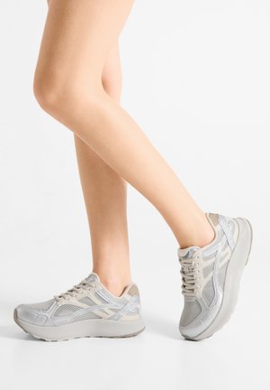Szare buty sportowe z siateczkową górą, wyściełanym kołnierzem i kontrastującymi akcentami. Zaokrąglony nosek i solidna podeszwa zaprojektowane dla komfortu i wsparcia.