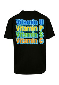Svart t-skjorte med flerfargede tekster som leser "Vitamin U," "Vitamin P," "Vitamin S," og "Vitamin C" i forskjellige fete skrifter og farger.