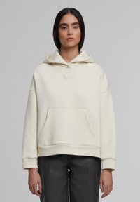 Helle Kapuzenjacke aus weichem Stoff, ausgestattet mit einer Kängurutasche, gerippten Bündchen und einem dezenten, auf der Brust gestochenen Logo.