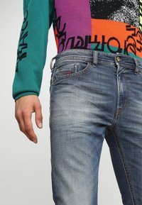 Skräddarsydda blå denimjeans med en urtvättad textur, som har en femfickorsdesign, bältesloopar och synliga sömdetaljer.
