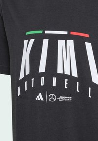 Černé bavlněné tričko s výrazným bílým textem "KIMI ANTONELLI" a zelenými, bílými a červenými pruhy nahoře. Loga značek Adidas a Mercedes jsou na spodní části.