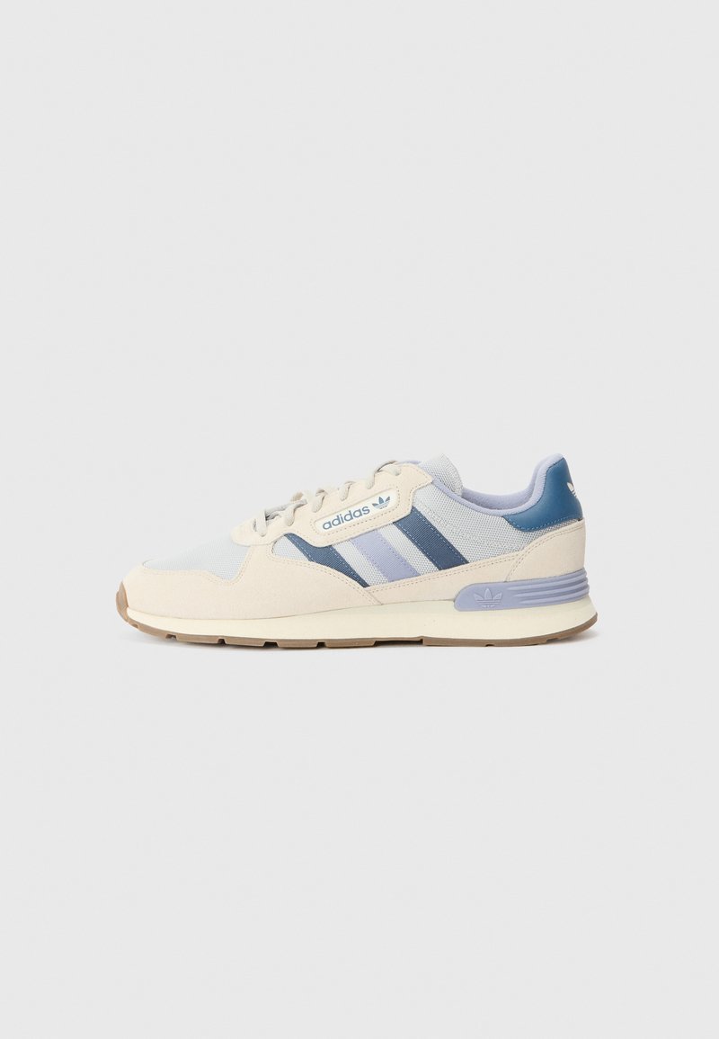 Shoe with a light cream mesh and suede upper, dark blue and lavender accents, featuring three stripes and a rubber sole with a textured grip.