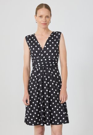 Black dress featuring a deep V-neck and sleeveless design, adorned with white polka dots, gathered at the waist for a flared silhouette.