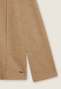 Manica di maglione marrone a coste con taglio dritto, caratterizzata da una piccola etichetta metallica vicino all'orlo e un tessuto morbido e testurizzato.