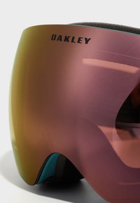 Oakley skidglasögon med en stor, böjd rosa lins med gradienttoning, svart logotyp och teal-accenter på ramen med texturerad skumisolering.