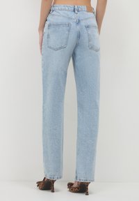 Jeans in denim azzurro chiaro con una vestibilità ampia, dotati di vita alta, due tasche posteriori e orlo grezzo. Abbinati a tacchi con stampa leopardata.