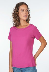 Kurzärmliges T-Shirt in lebhaftem Pink, mit einem Rundhalsausschnitt und glattem, leichtem Stoff, kombiniert mit lässigen blauen Jeans.