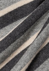 Gestreifter Strickstoff mit unterschiedlichen Bändern in Dunkelgrau, Hellgrau und Cremefarben. Weiche Textur mit sichtbaren Fasern und Variationen in der Webart.