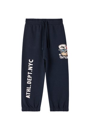 Pantaloni tuta in cotone blu navy con elastico in vita e nei polsini. Presentano una grafica da cartone animato e il testo bianco "ATHL. DEPT. NYC" lungo la gamba.