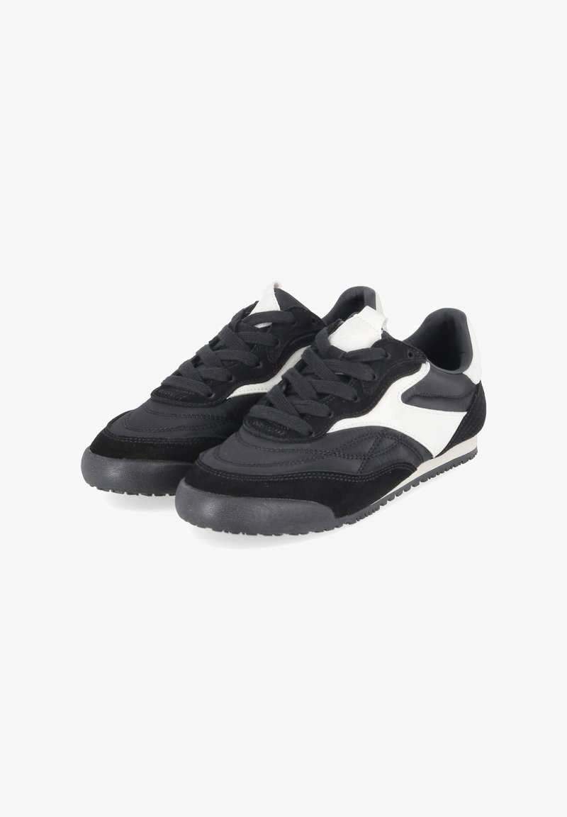 Paire de baskets basses noires et blanches à fermeture à lacets et semelles en caoutchouc texturées, inclinées vers la droite sur fond blanc.