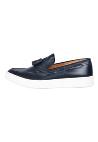 Scarpa slip-on in pelle blu con suola in gomma bianca, caratterizzata da dettagli di cucitura e una nappina decorativa sulla parte superiore.
