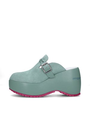 Zoccolo platform in suede verde chiaro con cinturino e fibbia, suola spessa e battistrada rosa, mostrato di profilo su sfondo bianco.