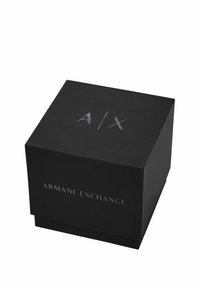 Caja de cartón negra con forma cuadrada. Presenta texto plateado en relieve "A/X" en la parte superior y "ARMANI EXCHANGE" en la parte frontal. Textura suave.