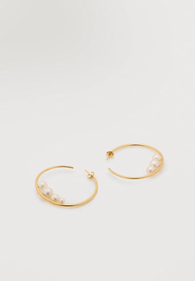 Χρυσά κρίκοι σκουλαρίκια, καθένας με τέσσερις μικρές λευκές πέρλες στη μια πλευρά, πάνω σε λευκό απλό φόντο.