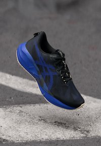 Baskets de course noires avec accents bleus, dotées d'un dessus texturé, d'un capuchon renforcé et d'un col rembourré. Semelle légère avec motifs de traction.