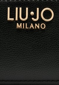 Portafoglio in pelle nera con superficie testurizzata. Logo del marchio in tono oro "LIU•JO MILANO" ben in vista. Design minimalista con linee pulite.