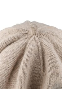Beige knitted beret featuring textured ribbed design, a small top knot, and soft, fuzzy wool texture.