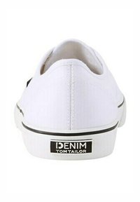 Sneakers in tela bianca con dettagli neri. Presentano una suola in gomma e una linguetta sul tallone con il marchio. Design pulito, profilo basso e semplici dettagli di cucitura.