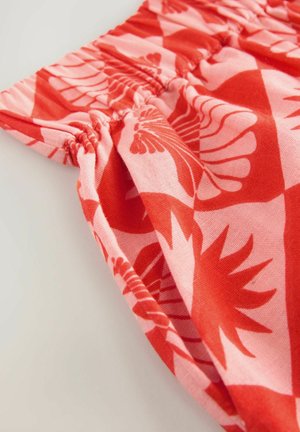 Tissu à motif floral rouge et rose avec une taille froncée et une texture douce, mettant en valeur des designs de feuilles et de coquillages intricats.