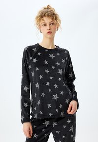 Zwart gemixt lounge-set met een lange mouw top voorzien van een witte sterrenprint en een zachte textuur, gecombineerd met bijpassende onderkant.