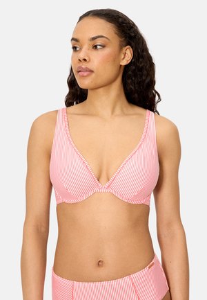 Mujer con cabello largo y rizado, vistiendo un top de bikini a rayas rosas y blancas y una parte inferior de talle alto a juego, mirando hacia un lado.