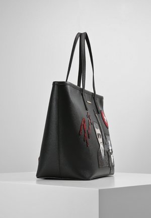 Sac fourre-tout en cuir noir avec deux poignées, comportant des patchs à sequins rouges et blancs ainsi que des motifs de personnages de dessin animé sur le côté.