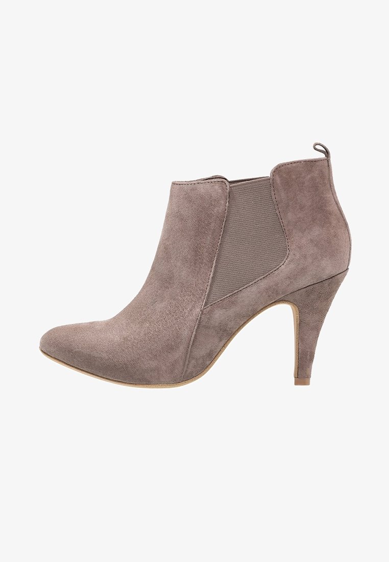 Bottine en daim taupe avec bout pointu, panneau latéral élastique, languette à l'arrière et talon fin de hauteur moyenne.