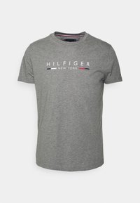 Grå T-shirt med kort ärm och texten "Hilfiger New York" samt marinblå, vit och röd rand på bröstet, rund halsdesign.
