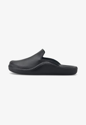 Black leather slip-on clog with textured upper, curved design, and a padded interior. Flat rubber sole for comfort and stability.