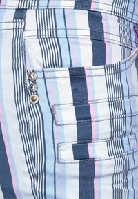 Randig tyg i blått, rosa och vitt; har flera fickor; inkluderar metallackcenter i fickområdet.