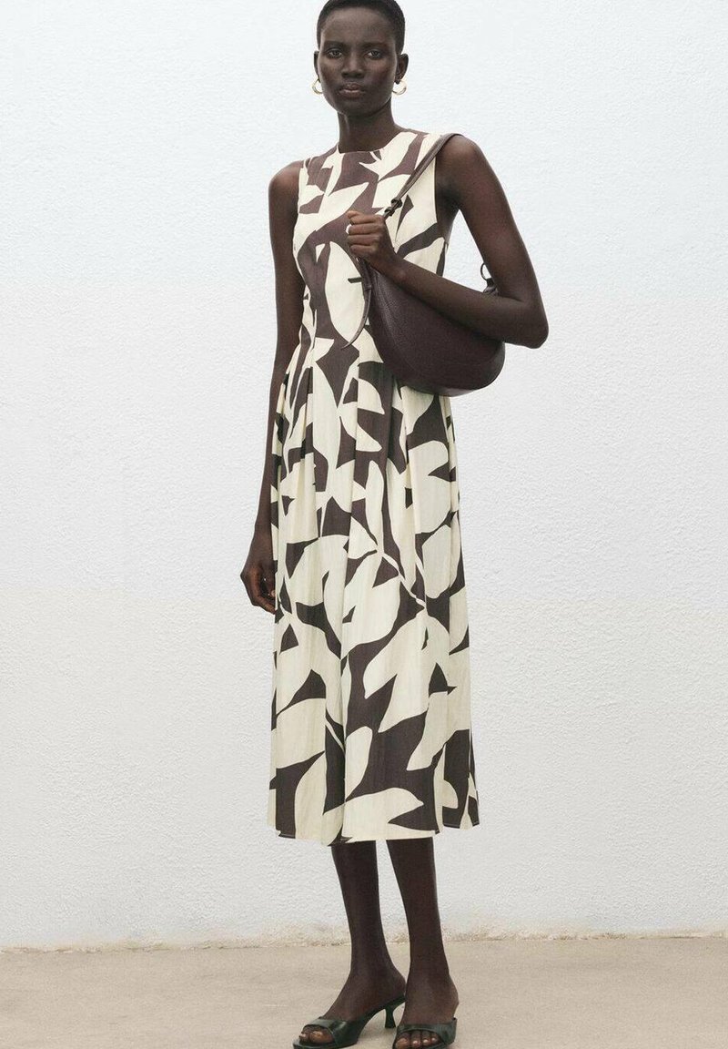 Vestido marrón y blanco con estampado, con un cuerpo entallado y una falda fluida; combinado con un bolso de hombro marrón y sandalias verdes.