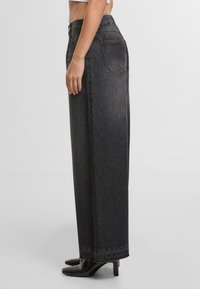 Černé denimové široké kalhoty s elastickým pasem, které mají dvě zadní kapsy a švy na lemu.