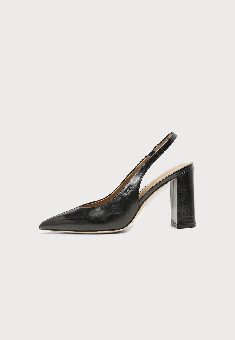 Chaussure slingback en cuir noir à bout pointu avec un talon bloc haut et une doublure intérieure beige sur un fond clair uni.
