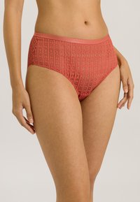 Hooggesneden koraalkleurig ondergoed met een gestructureerd patroon en een gladde tailleband, voorzien van delicate streepjes in de stof.