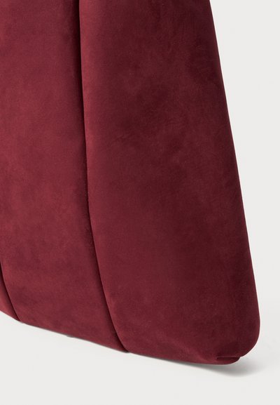 Burgundin nahkalaukku, jossa on sileä pinta, rakenteellinen muoto ja ommellut paneelit, sopii erilaisiin tilaisuuksiin.