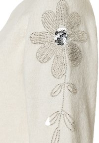 Cremefarbener Pullover mit einem Perlenblumendesign auf der Schulter, verziert mit silbernen Pailletten und zarten Blumenmustern im Strick.