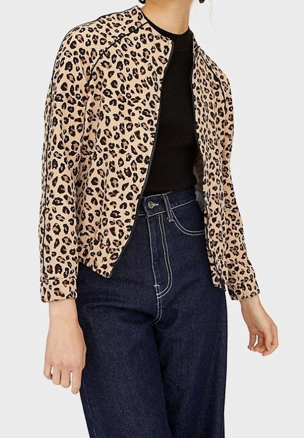 Giacca in stampa leopardata beige, caratterizzata da un colletto rotondo, maniche lunghe e un design corto. Abbinata a jeans blu a vita alta.