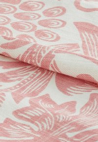 Textil cu un fundal crem și modele botanice mari roze. Material moale, țesut, cu o suprafață ușor texturată.