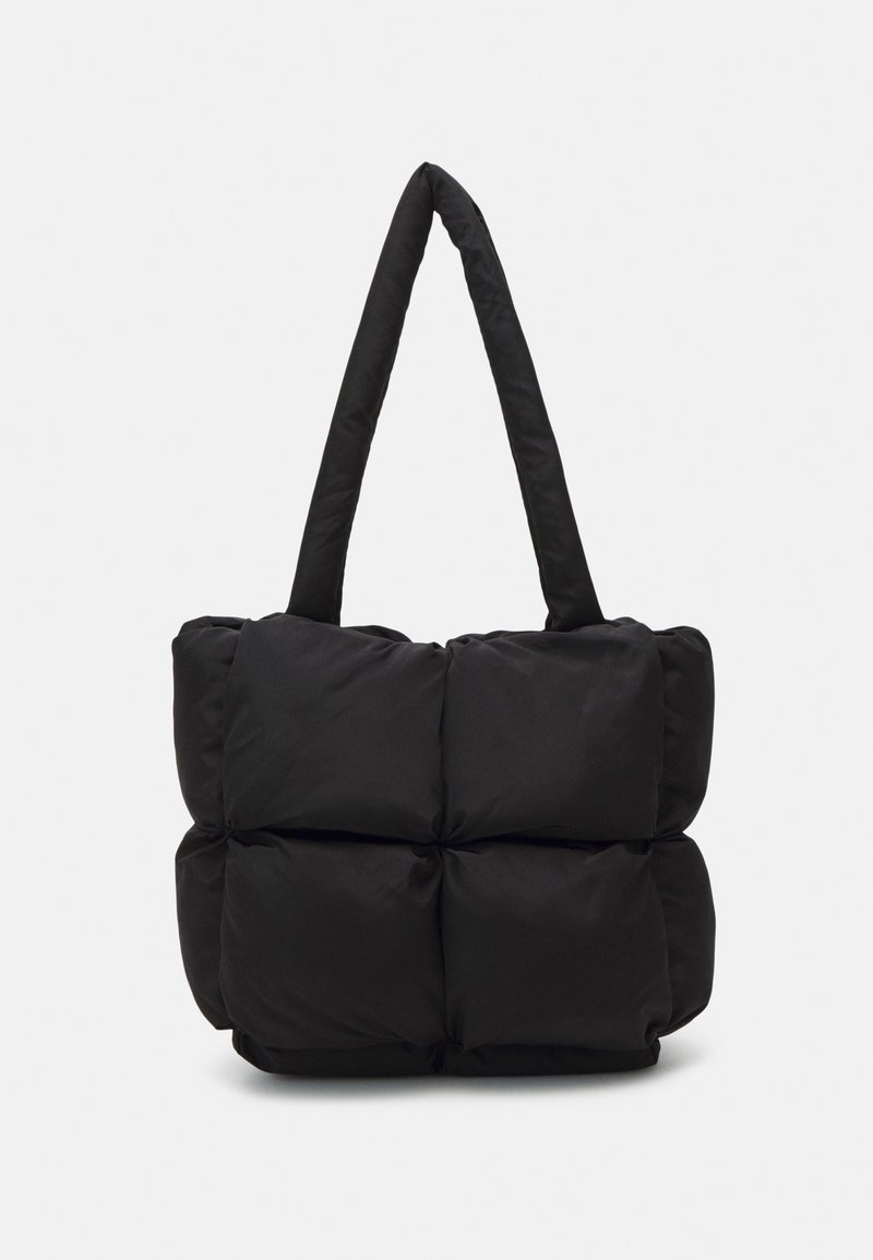 Sac cabas matelassé noir avec quatre grandes sections carrées matelassées et deux longues bretelles matelassées.