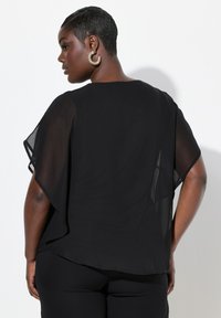 Schwarzes, transparentes Oberteil aus lockerem Stoff mit Kapuzenärmel und rundem Ausschnitt. Eine subtile Textur verstärkt das fließende Design.