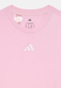 Rosa bomull t-skjorte med korte ermer, rund hals og en hvit Adidas-logo på brystet. Merke synlig med størrelsesinformasjon.