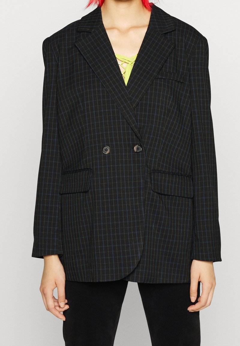 Černý kostkovaný oversized blazer s modrými pruhy, dvojřadové knoflíky, zářezovými klopami a dvěma předními kapsami. Hladká textura.