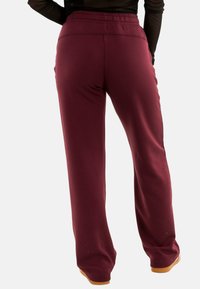 Pantalons de jogging bordeaux avec une coupe décontractée, une taille élastique et des jambes fuselées, fabriqués à partir d'un tissu doux et extensible pour le confort.
