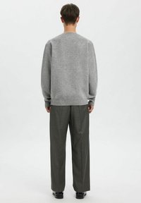 Grå ullgenser med rund hals, lange ermer og ribbestrikket kant, kombinert med rutete bukser med høyt liv og løs passform.